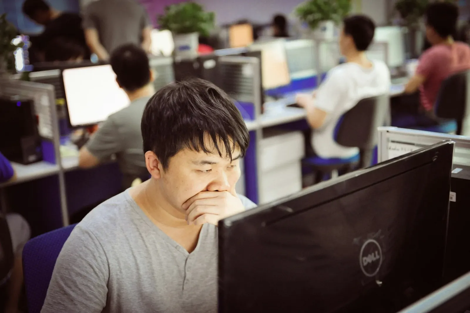 Tired worker at a desk in a busy open-plan office