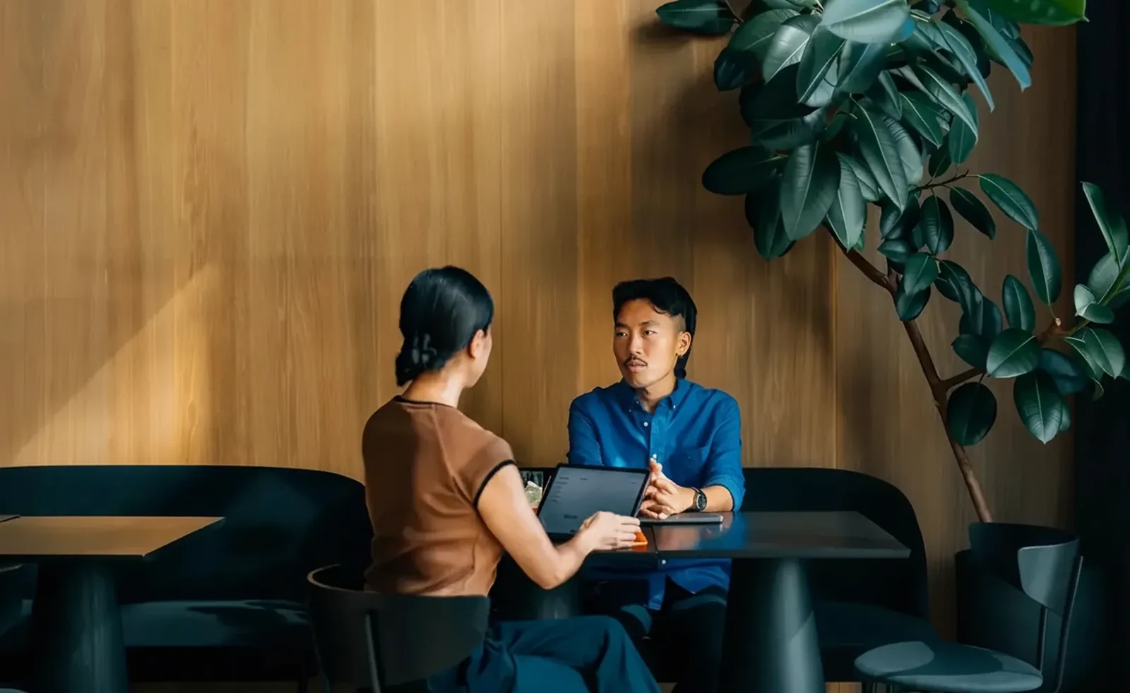 Two colleagues talking on a lounge in a plant-filled office